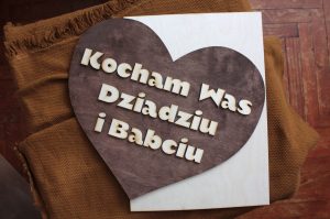 Drewniane serce z ciemnego drewna z jasnym napisem " Kocham Was Dziadziu i Babciu"