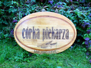 Zdjęcie przedstawia szyld w stylu vintage z napisem " Córka piekarza"